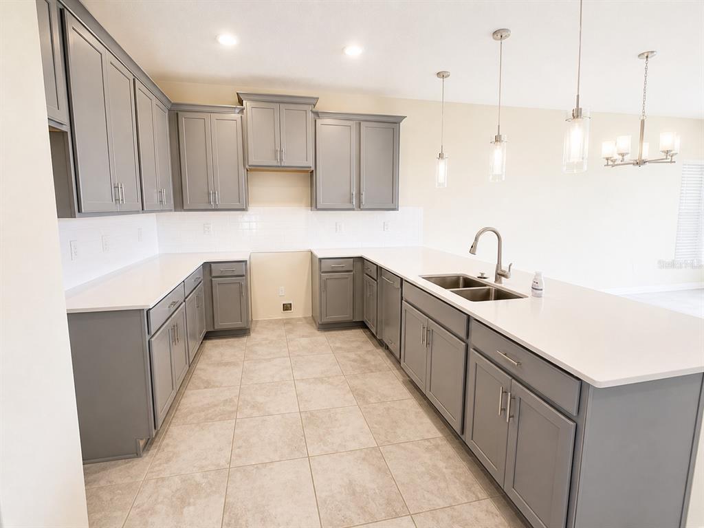 A kitchen features gray cabinets, white countertops, a double-basin sink, and light-colored tile flooring — 505 OCEAN COURSE AVENUE UNIT 505, DAVENPORT, FL