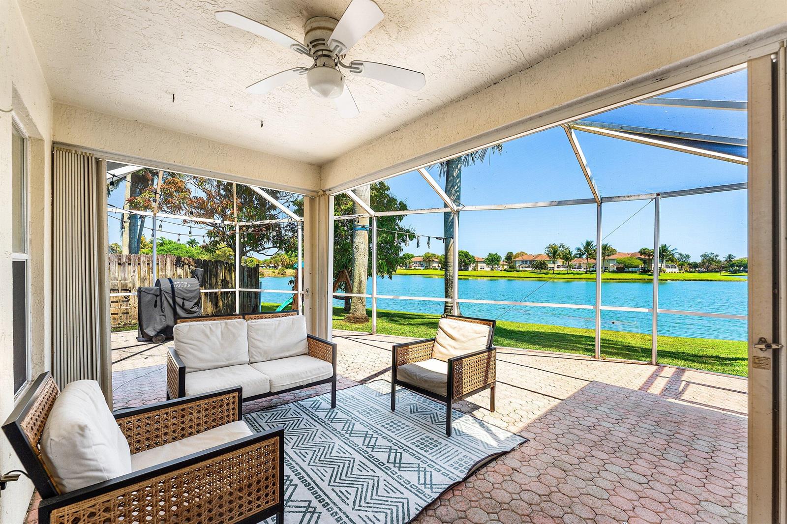 A screened-in patio features outdoor furniture, a ceiling fan, and a view of a lake — 29 Swallow Drive, Boynton Beach FL 33436, BOYNTON BEACH, FL