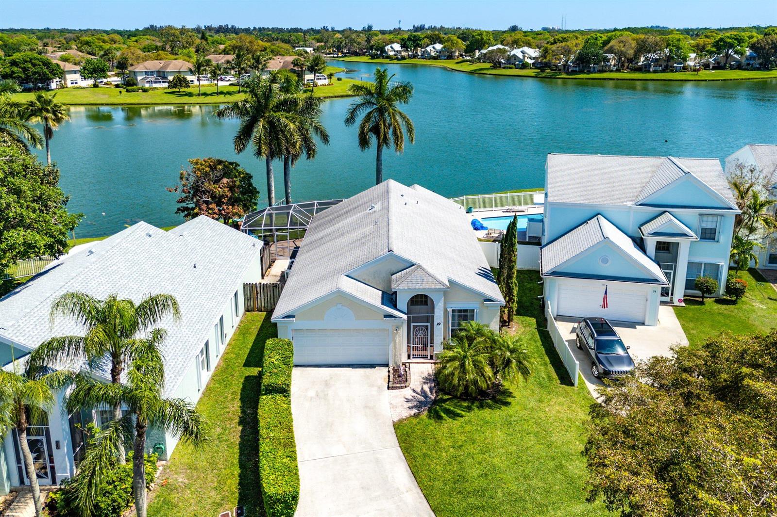 An aerial view shows three suburban houses with pools along a lakefront — 29 Swallow Drive, Boynton Beach FL 33436, BOYNTON BEACH, FL
