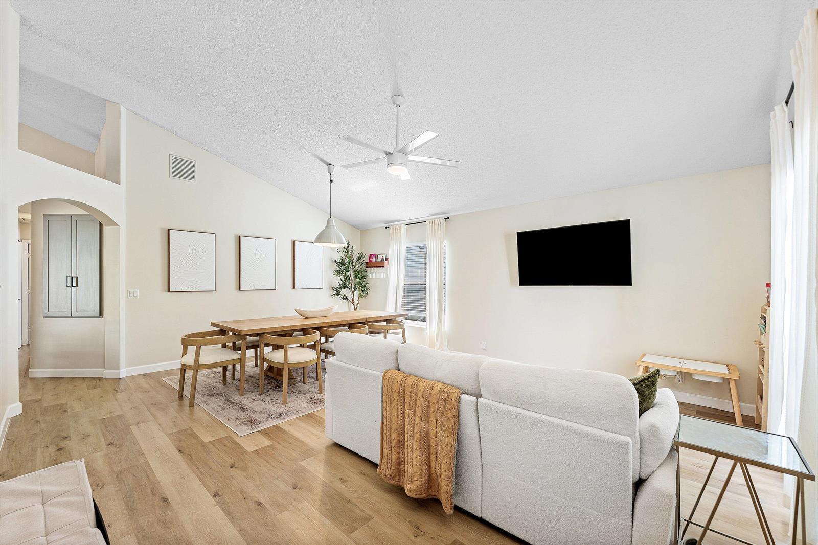 A bright living and dining room features light wood floors, a white sofa, and vaulted ceilings — 29 Swallow Drive, Boynton Beach FL 33436, BOYNTON BEACH, FL