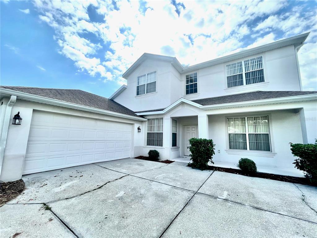 A two-story white house with a garage and a concrete driveway under a blue sky — 2370 HINSDALE DRIVE, KISSIMMEE, FL