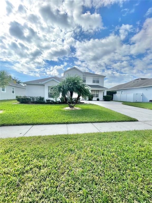 A two-story suburban house features a palm tree in the front yard under a cloudy sky — 2370 HINSDALE DRIVE, KISSIMMEE, FL