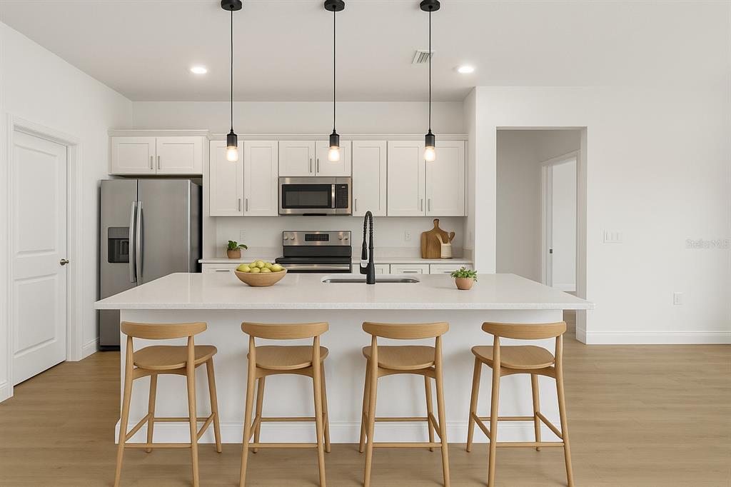 A modern kitchen features white cabinetry, stainless steel appliances, and a large central island — 16954 SW 39TH CIRCLE, OCALA, FL