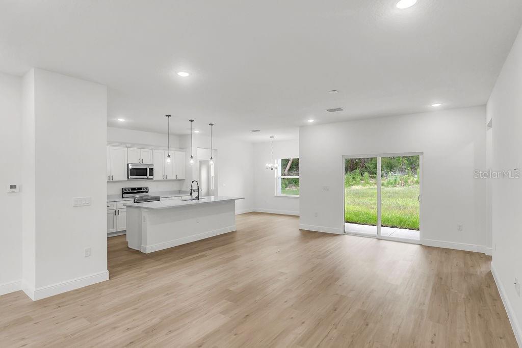 An open-concept kitchen and living area with white cabinetry, a center island, and sliding doors — 16954 SW 39TH CIRCLE, OCALA, FL