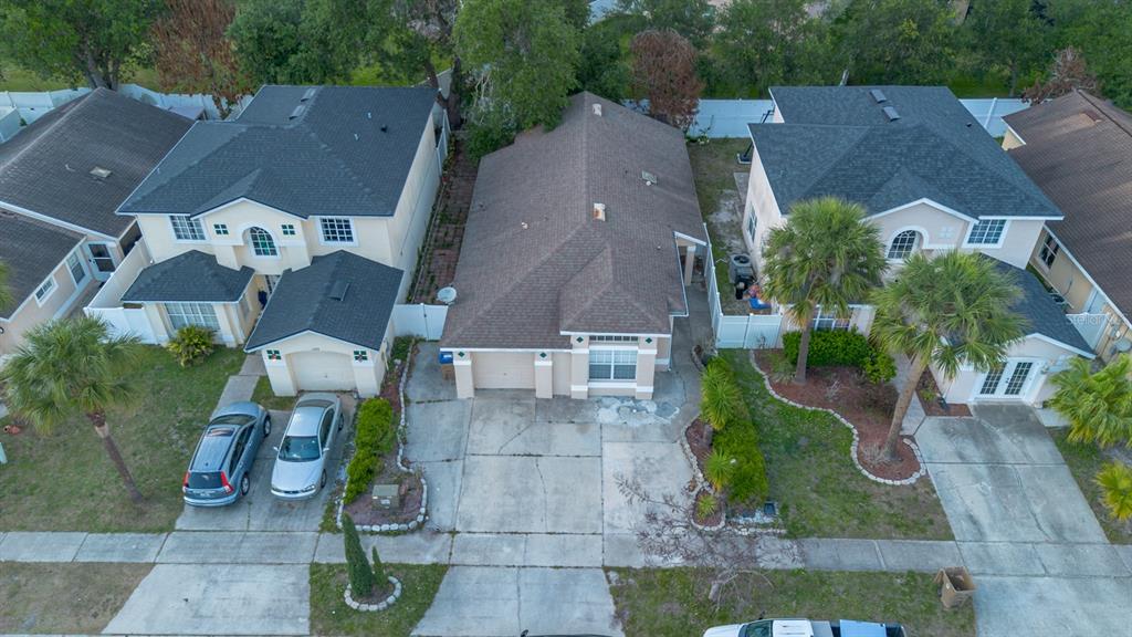 An aerial view shows three suburban houses with driveways and palm trees in a neighborhood — 3267 BREWSTER DRIVE, KISSIMMEE, FL