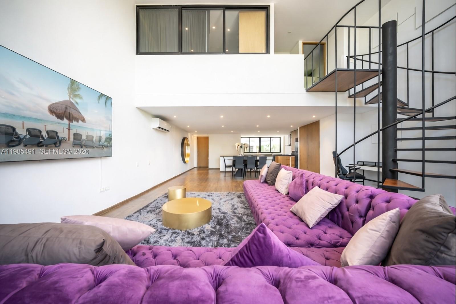 A spacious living room features a large purple tufted sofa, gold coffee tables, and a spiral staircase — 0 Avenida CTM # 107, TX 77728, TX