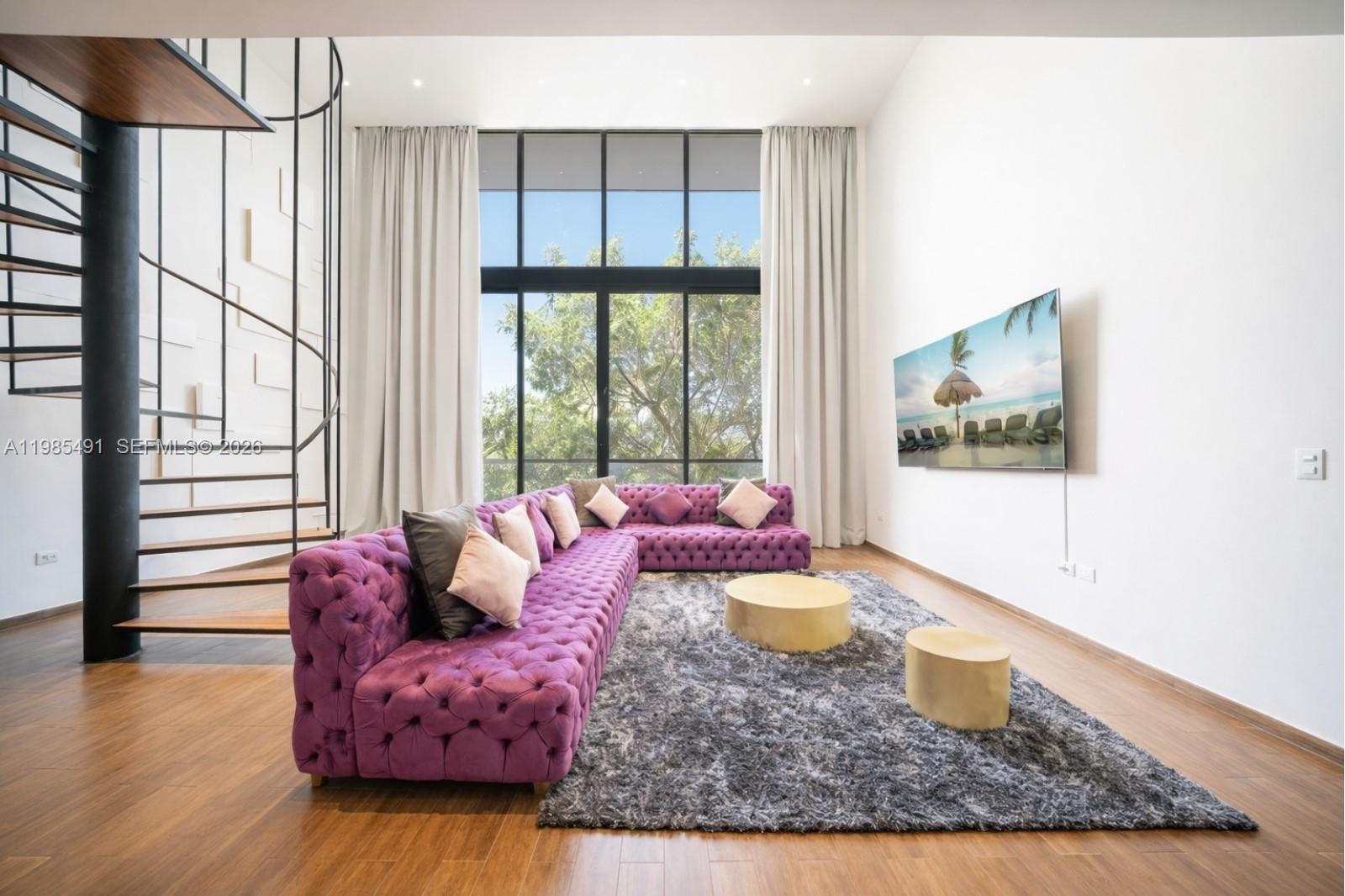 A living room features a large purple tufted sectional, a spiral staircase, and floor-to-ceiling windows — 0 Avenida CTM # 107, TX 77728, TX