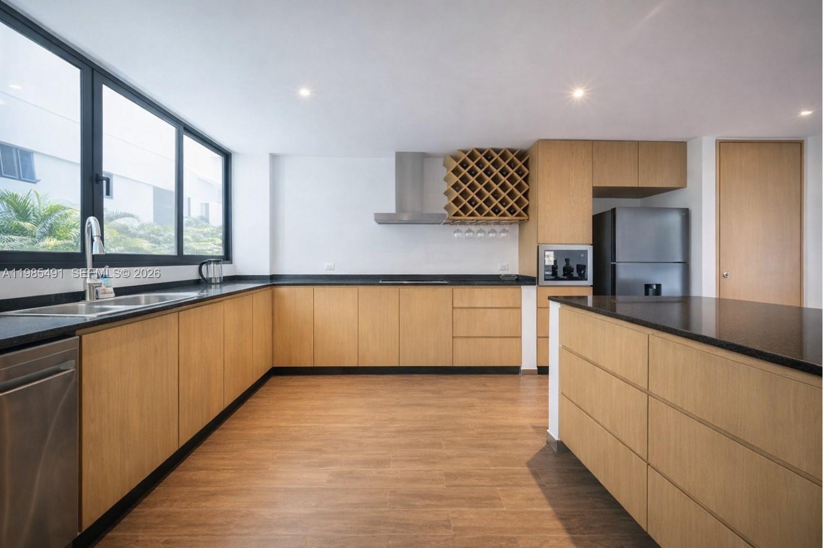 A modern kitchen features light wood cabinets, black countertops, stainless steel appliances, and a wine rack — 0 Avenida CTM # 107, TX 77728, TX