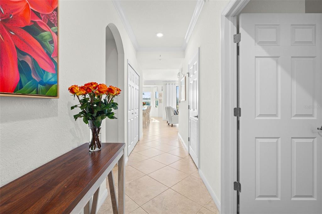 A hallway with tile floors, white doors, and a console table with flowers leads forward — 16904 VARDON TERRACE UNIT 107, BRADENTON, FL