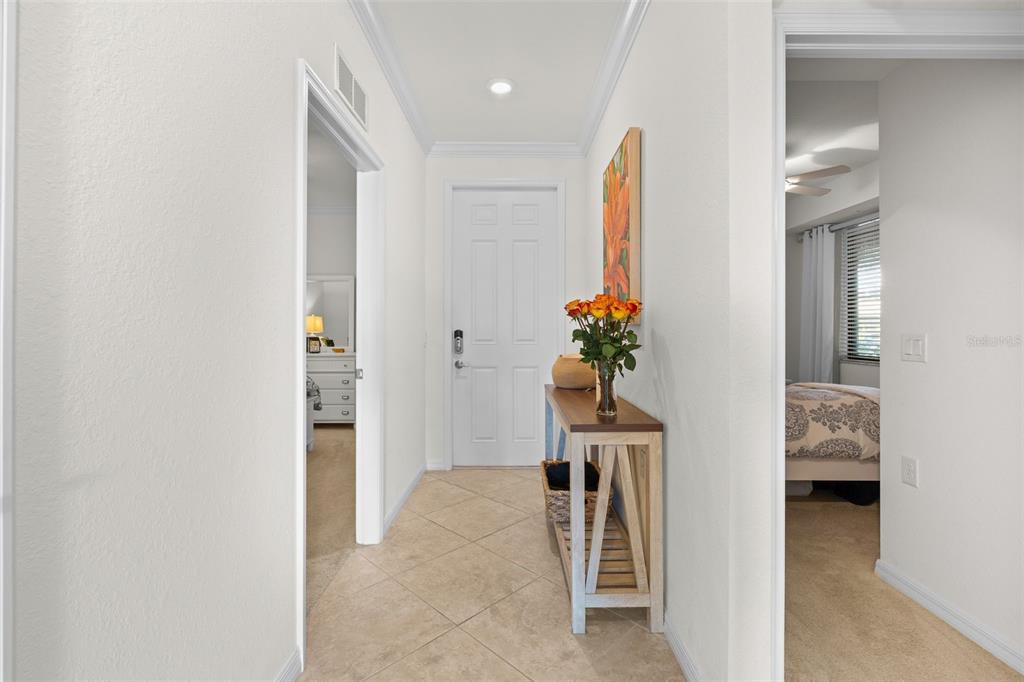 A tiled entryway features a console table with flowers and doorways leading to bedrooms — 16904 VARDON TERRACE UNIT 107, BRADENTON, FL