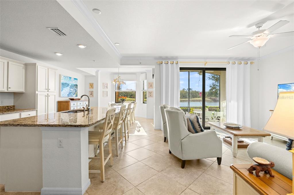 An open-concept kitchen and living area features granite countertops, tile flooring, and a lake view — 16904 VARDON TERRACE UNIT 107, BRADENTON, FL