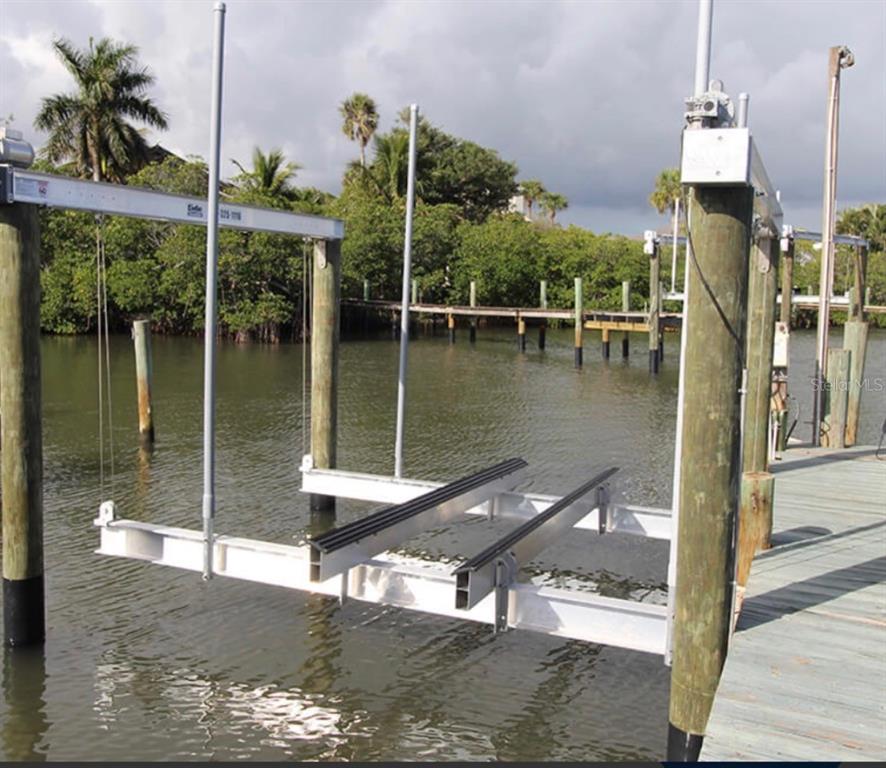 A boat lift with aluminum rails and guide poles sits in the water beside a dock — 1739 BAYOU GRANDE BOULEVARD NE, ST PETERSBURG, FL