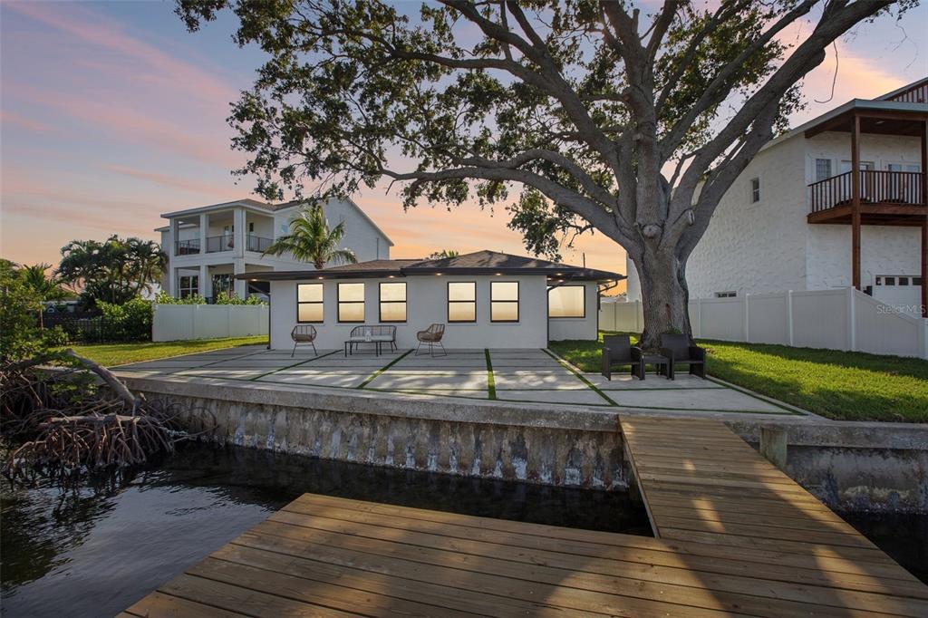 A waterfront house with a concrete patio, a large tree, and a wooden dock — 1739 BAYOU GRANDE BOULEVARD NE, ST PETERSBURG, FL