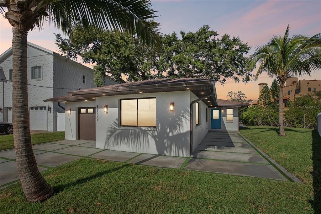 A single-story house with a white stucco exterior, a blue front door, and concrete pavers — 1739 BAYOU GRANDE BOULEVARD NE, ST PETERSBURG, FL