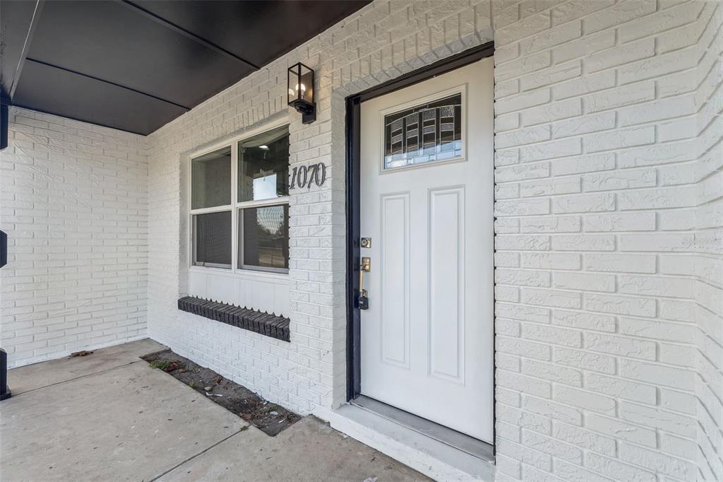 A white brick exterior features a front door, a window, and a black porch ceiling — 1070 N LIBBY COURT, DAYTONA BEACH, FL