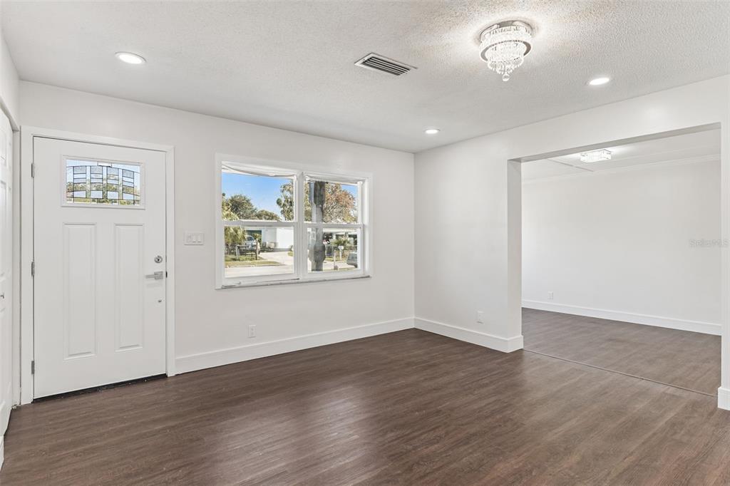 An interior room with white walls, dark wood-look flooring, a front door, and a chandelier — 1070 N LIBBY COURT, DAYTONA BEACH, FL
