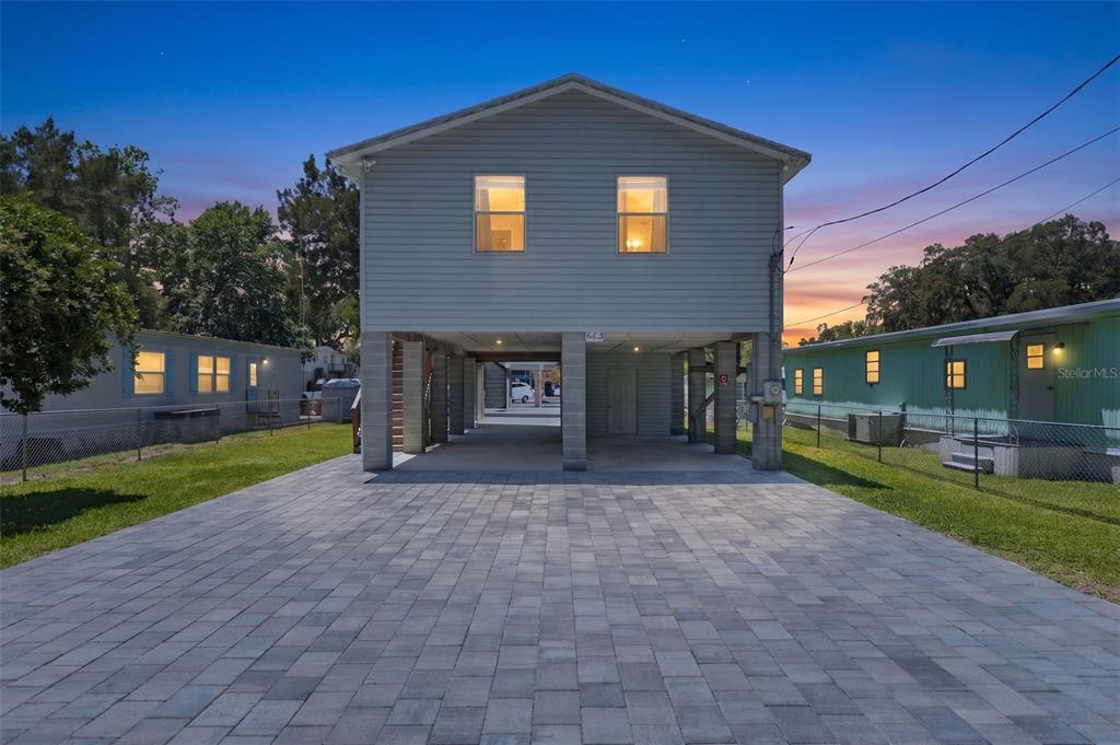 A two-story elevated house with a paved driveway sits between two mobile homes — 6183 WAVERLY ROAD, WEEKI WACHEE, FL