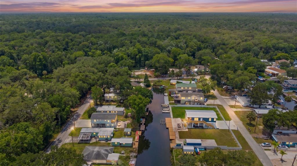 An aerial view shows houses situated along a narrow canal surrounded by dense green trees — 6183 WAVERLY ROAD, WEEKI WACHEE, FL