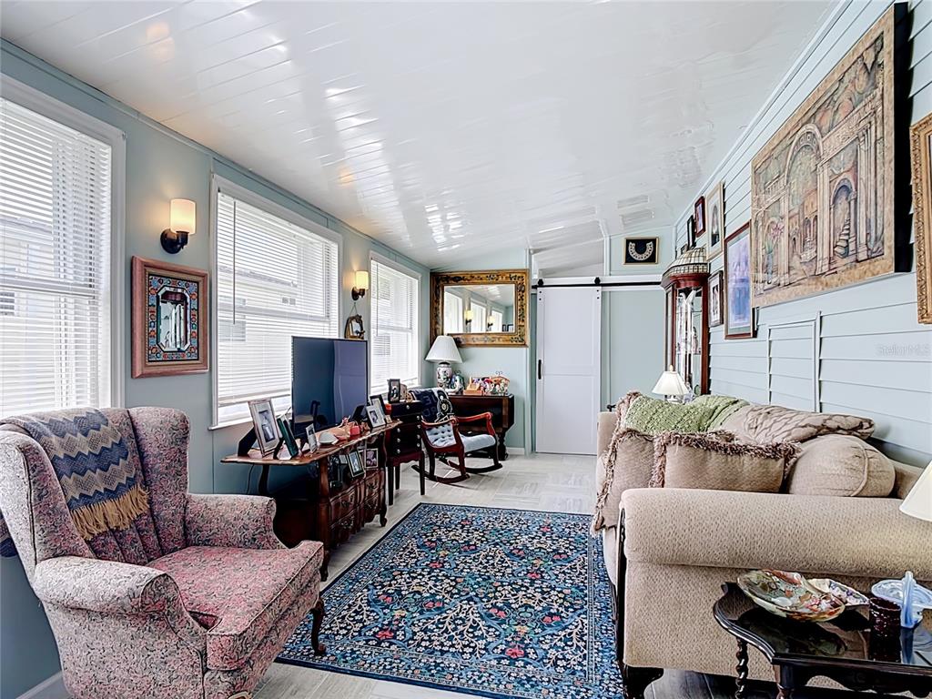 A living room features light blue walls, a glossy white ceiling, and a patterned rug — 9000 US HWY 192 UNIT 297, CLERMONT, FL