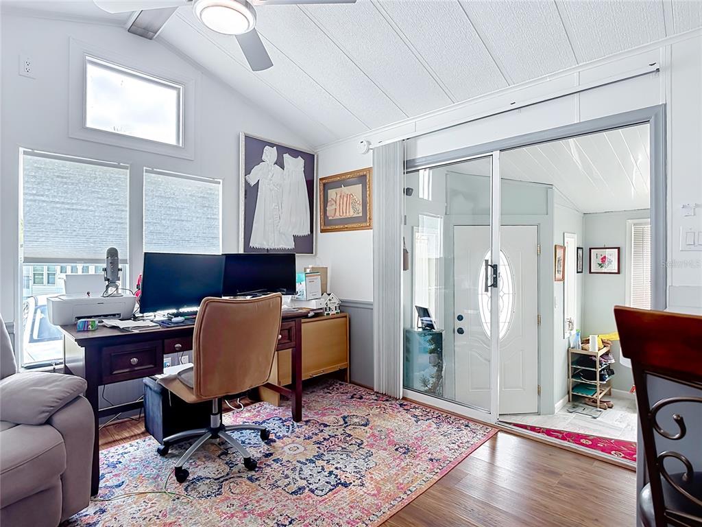 A home office features a desk, dual monitors, a patterned rug, and sliding glass doors — 9000 US HWY 192 UNIT 297, CLERMONT, FL