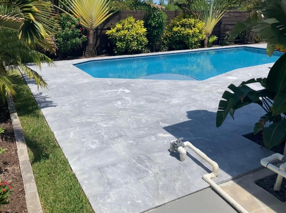 A swimming pool with a grey stone patio and tropical landscaping in a backyard — 702 Grove Street, FL 33461, FL