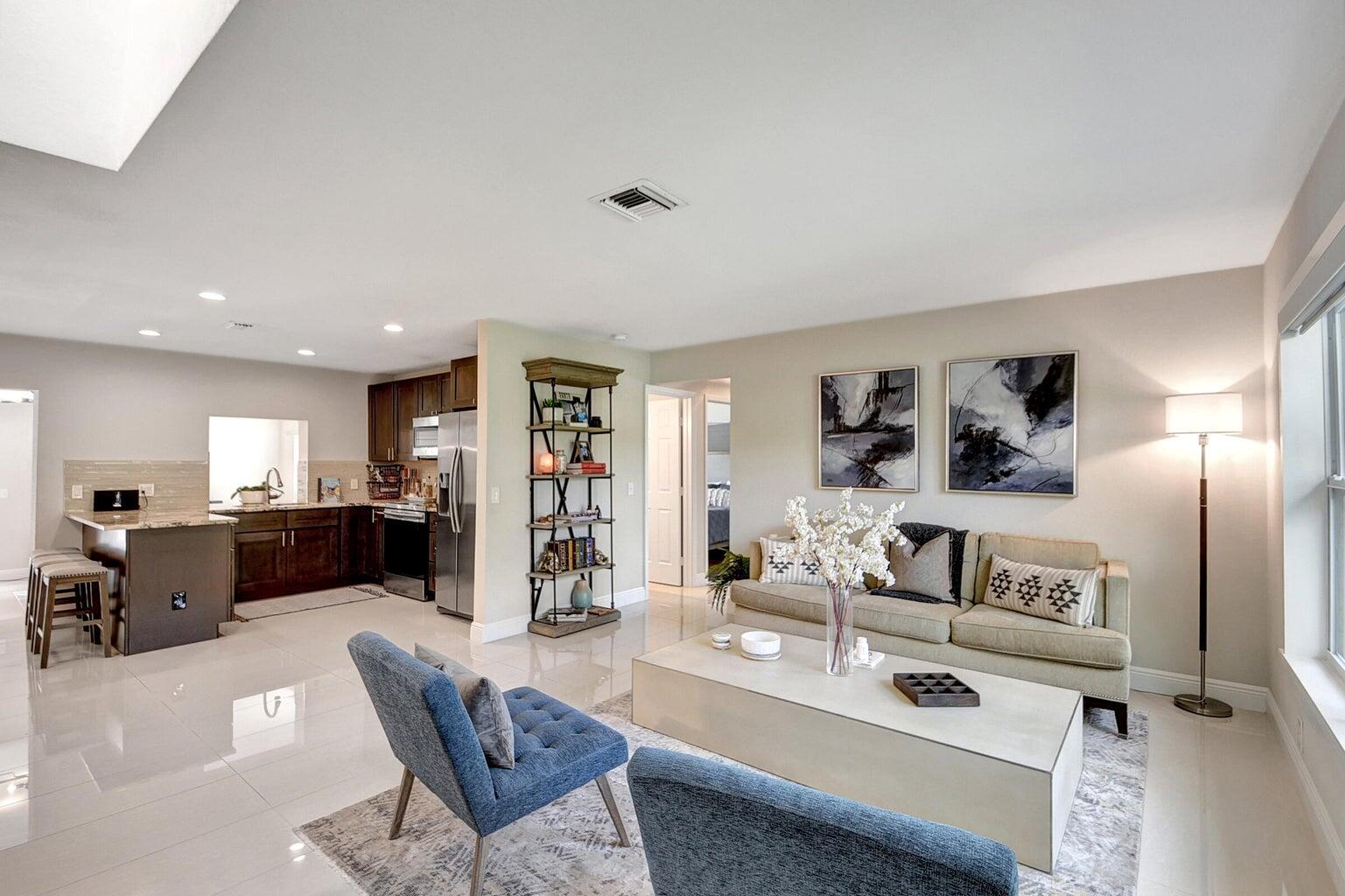 A living room with light tile floors, a beige sofa, and an open-concept kitchen — 702 Grove Street, FL 33461, FL