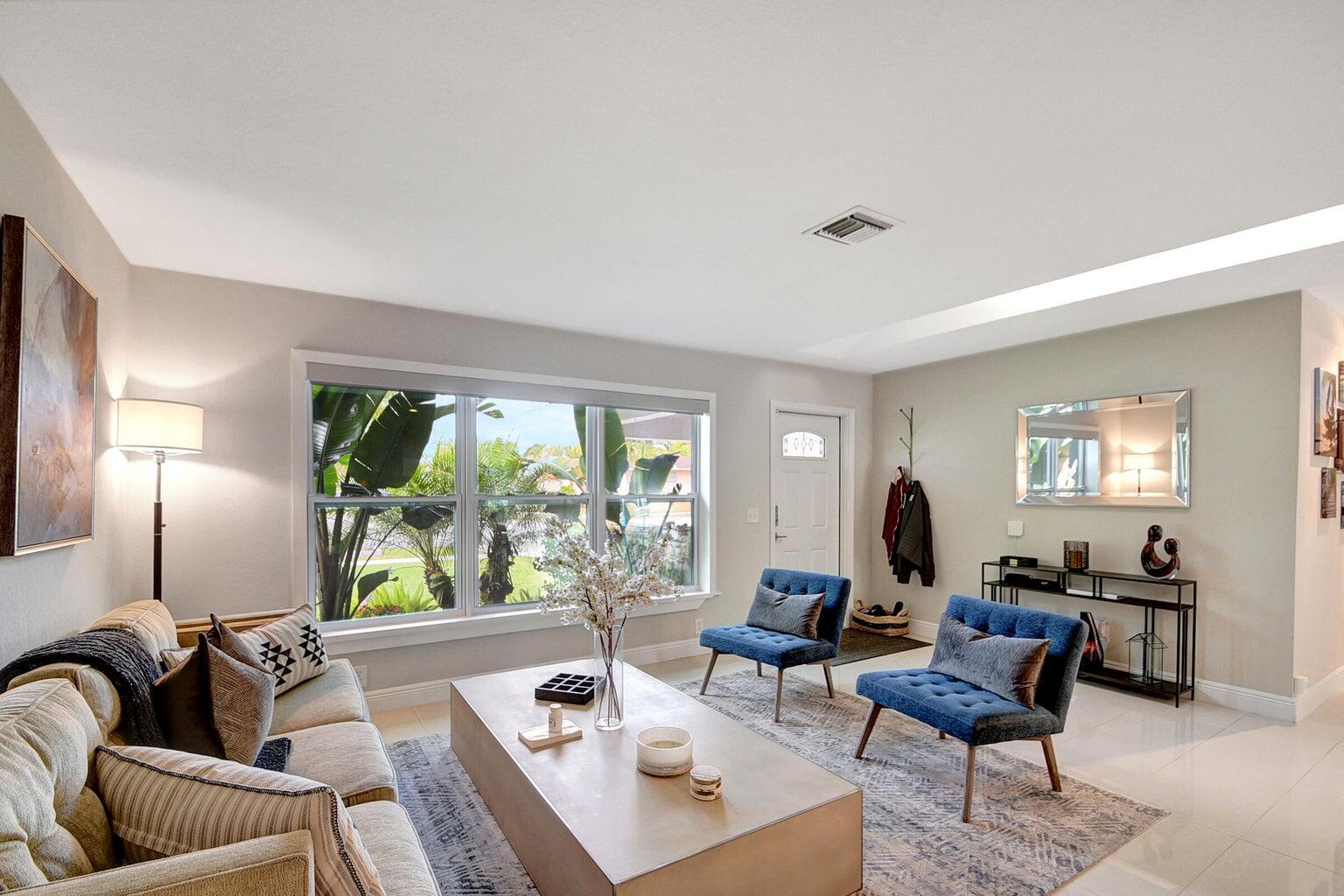 A living room features a beige sofa, two blue chairs, a coffee table, and windows — 702 Grove Street, FL 33461, FL