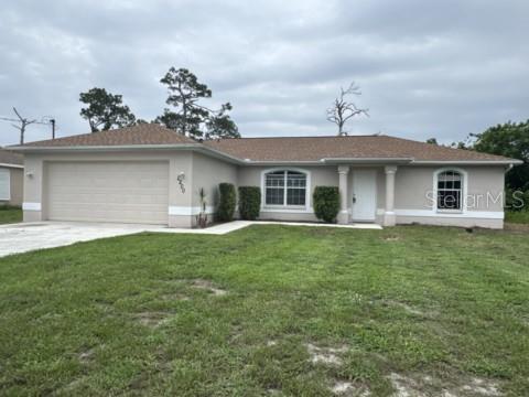 A single-story house with a tan stucco exterior, a two-car garage, and a shingled roof — 2200 TOPSY TERRACE, NORTH PORT, FL