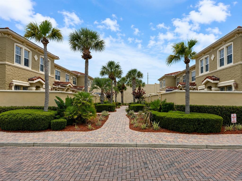A paved walkway leads between two tan residential buildings lined with palm trees and landscaping — 3008 BELLA VISTA DRIVE, DAVENPORT, FL