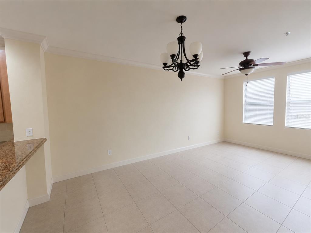An empty dining area features tile floors, a chandelier, a ceiling fan, and windows — 3008 BELLA VISTA DRIVE, DAVENPORT, FL
