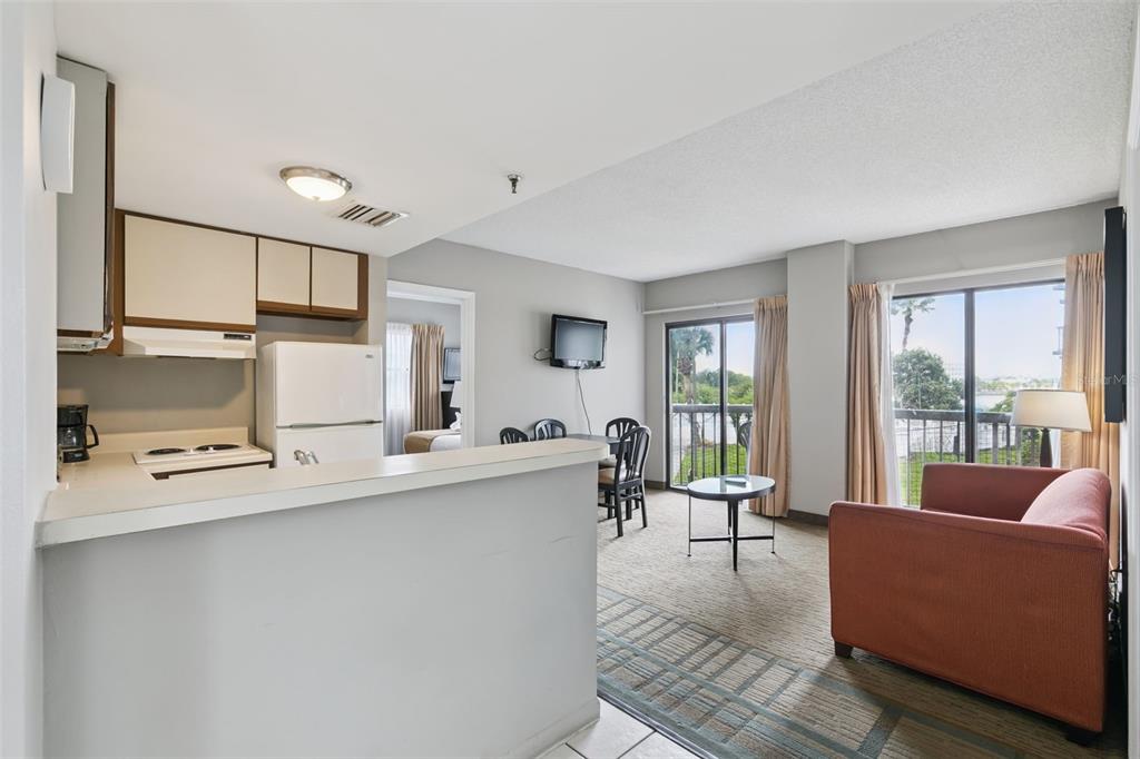 A kitchen with a breakfast bar overlooks a living area with a sofa and balcony — 6165 CARRIER DRIVE UNIT 2201, ORLANDO, FL