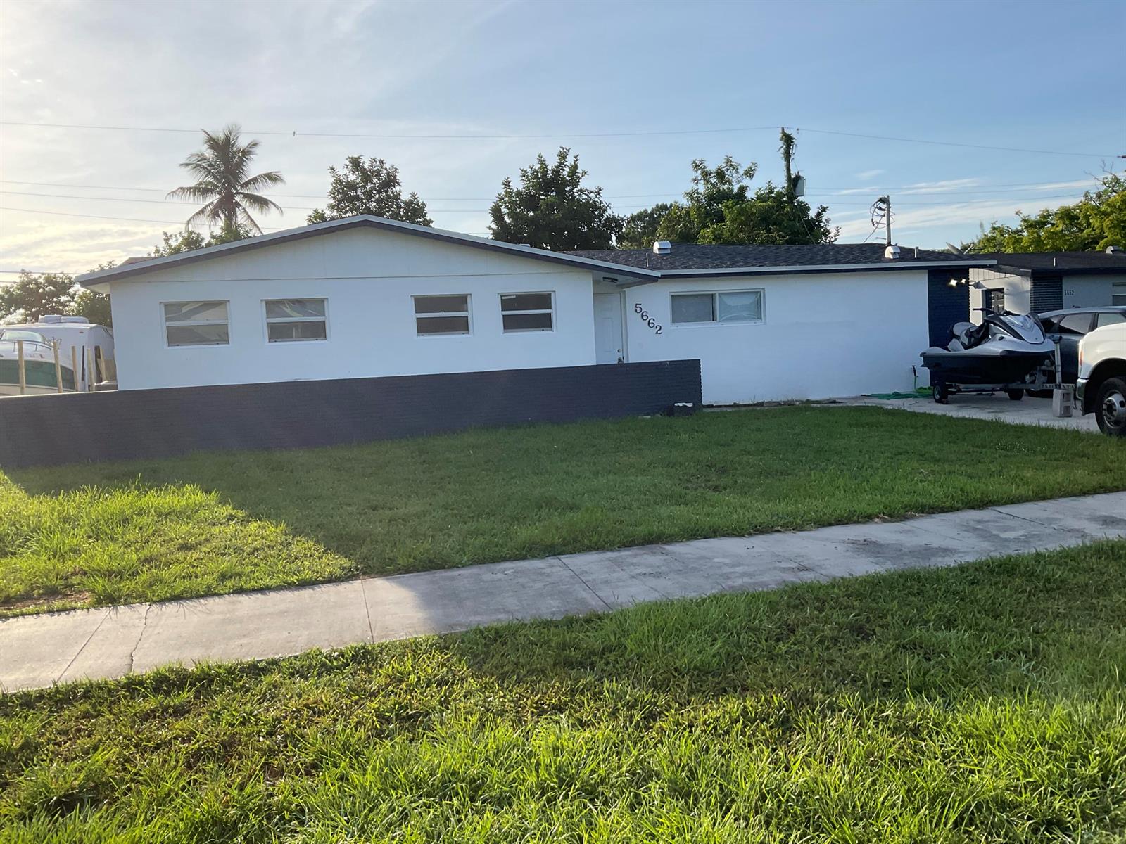 A single-story white house features a dark gray wall and a front lawn — 5662 Parke Avenue, West Palm Beach FL 33407, WEST PALM BEACH, FL