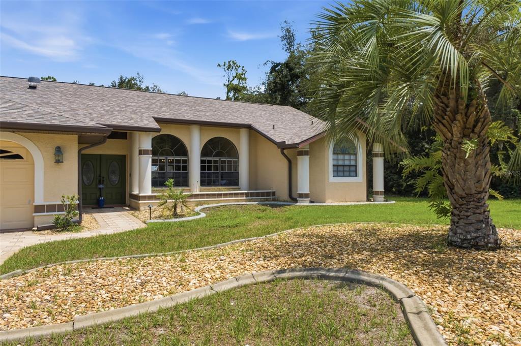A single-story house with a beige stucco exterior, arched windows, and a palm tree — 10307 WATERS EDGE COURT, WEEKI WACHEE, FL