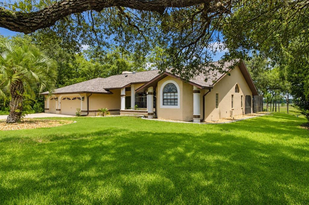 A tan single-story house with a multi-car garage and a large green lawn — 10307 WATERS EDGE COURT, WEEKI WACHEE, FL