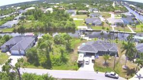 An aerial view shows two houses with driveways situated along a canal in a residential neighborhood — 9186 IMPALA CIRCLE, PORT CHARLOTTE, FL