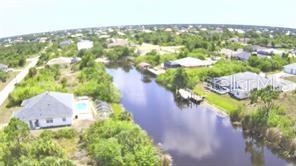 An aerial view of a canal-front residential neighborhood with houses, pools, and boat docks — 9186 IMPALA CIRCLE, PORT CHARLOTTE, FL