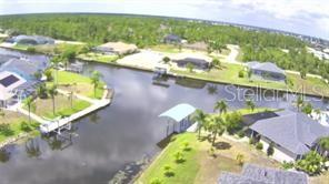 An aerial view of a canal-front residential neighborhood with houses, boat docks, and lush vegetation — 9186 IMPALA CIRCLE, PORT CHARLOTTE, FL