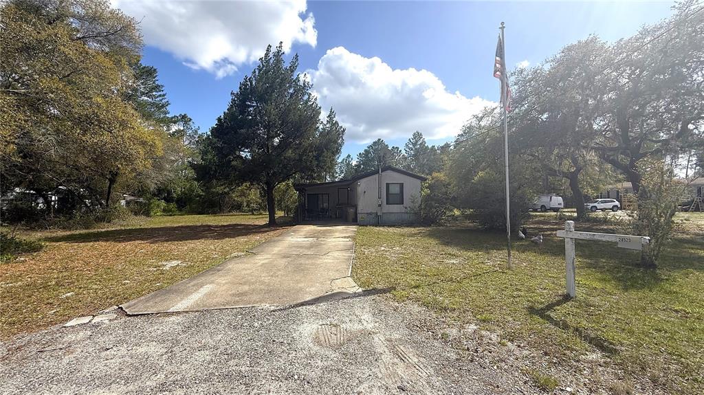 A single-story mobile home with a concrete driveway and a flagpole in the front yard — 28520 HOLLY AVENUE, PAISLEY, FL