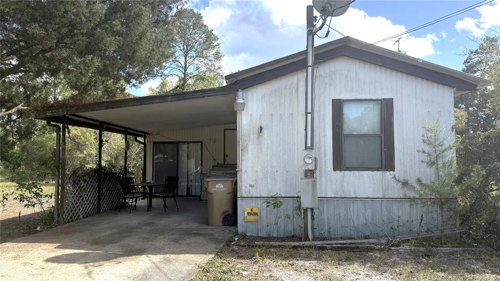 A single-story mobile home with a carport, a sliding glass door, and a brown window — 28520 HOLLY AVENUE, PAISLEY, FL