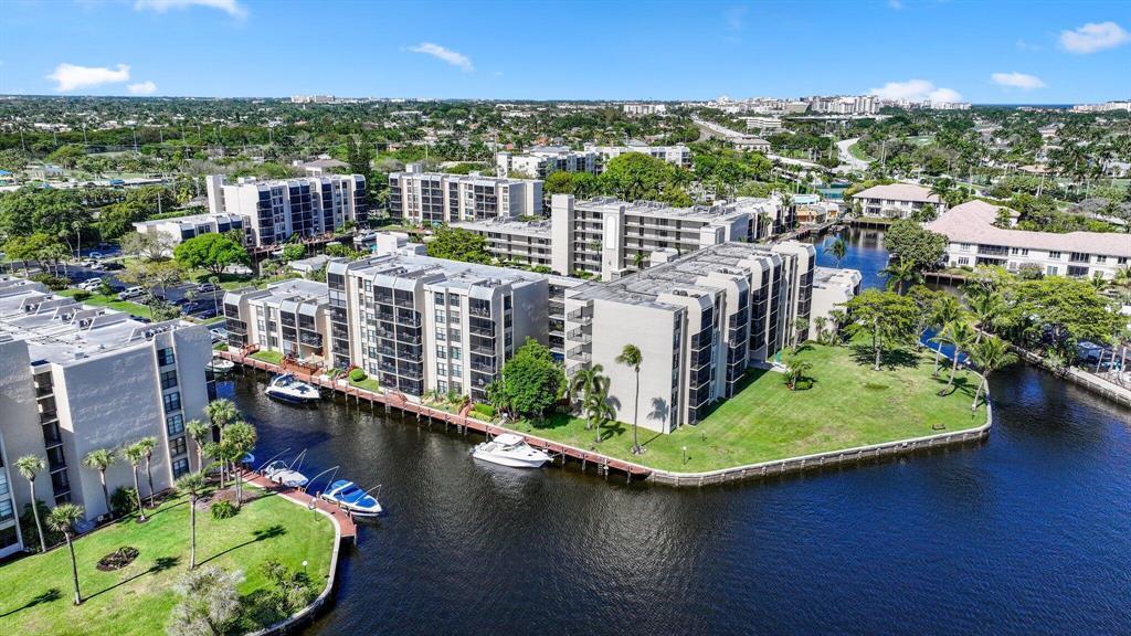 An aerial view of multi-story apartment buildings situated along a canal with docked boats — 9 Royal Palm Way # 102, Boca Raton FL 33432, BOCA RATON, FL