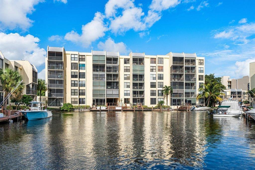 A multi-story apartment building sits along a canal with several boats docked in front — 9 Royal Palm Way # 102, Boca Raton FL 33432, BOCA RATON, FL