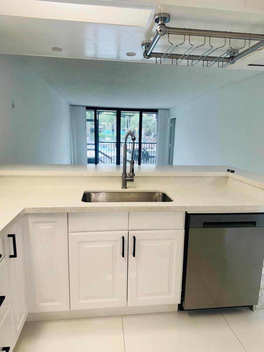A kitchen with white cabinets, a stainless steel sink, and a dishwasher overlooking a patio — 9 Royal Palm Way # 102, Boca Raton FL 33432, BOCA RATON, FL