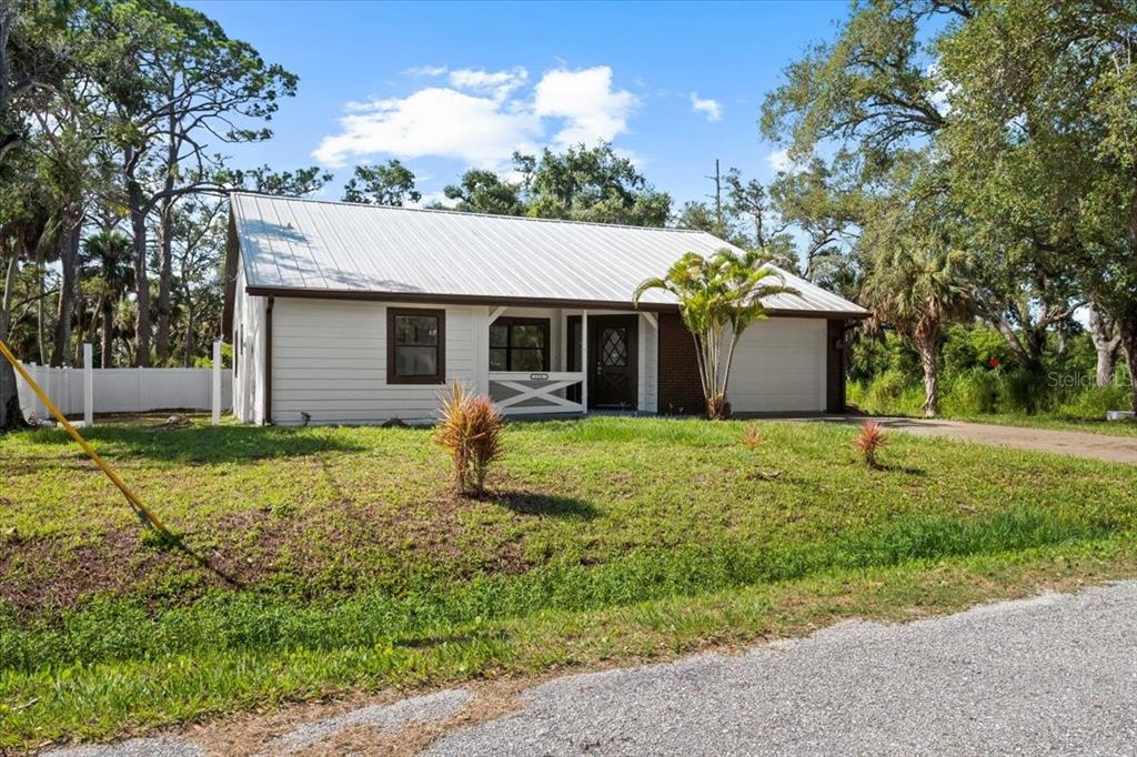 A single-story house with a white metal roof, horizontal siding, and a front porch — 116 HERMES ROAD, VENICE, FL