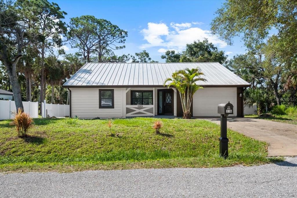 A single-story house with a metal roof, white siding, and a front porch — 116 HERMES ROAD, VENICE, FL