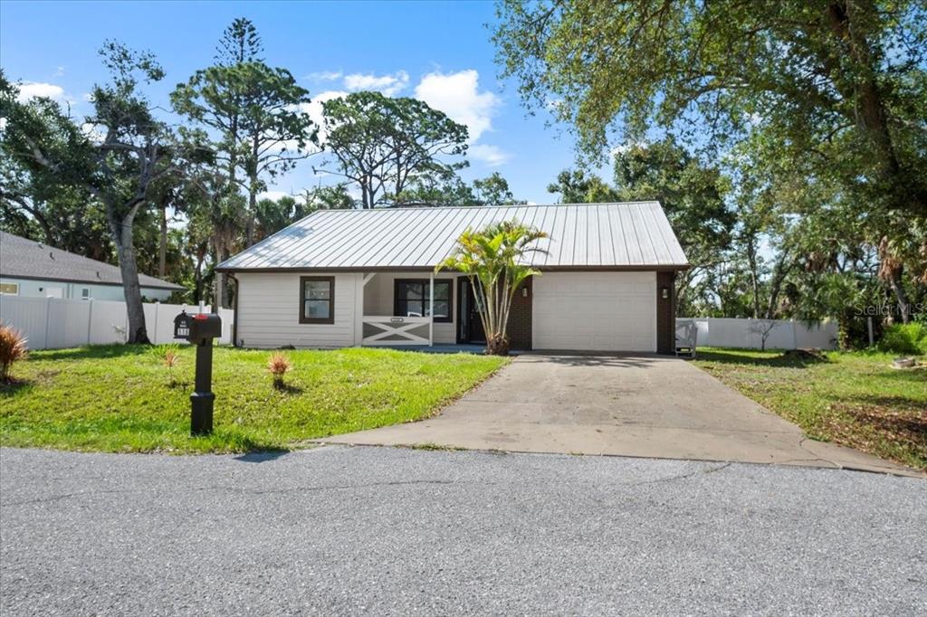 A single-story house with a metal roof, a front porch, and a concrete driveway — 116 HERMES ROAD, VENICE, FL