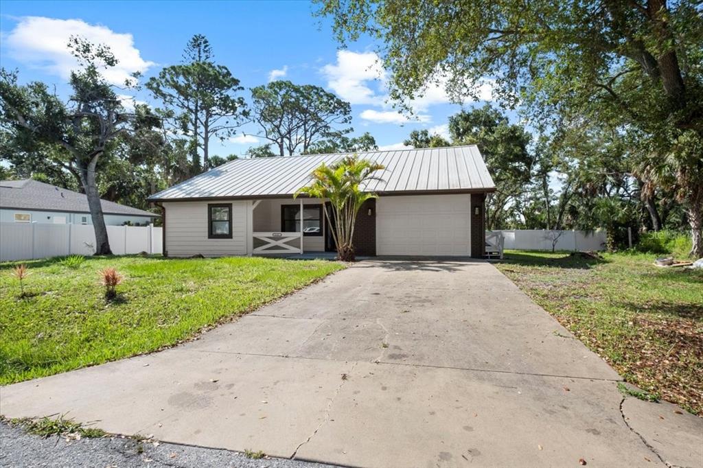 A single-story house with a metal roof, a concrete driveway, and a small front porch — 116 HERMES ROAD, VENICE, FL