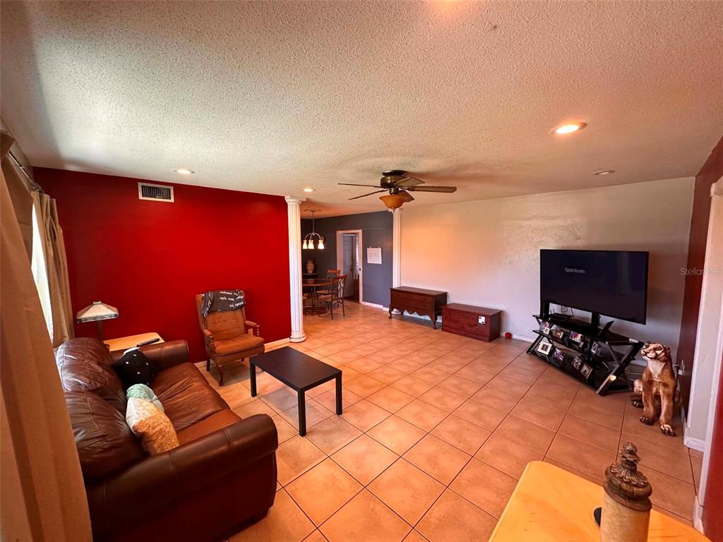 A living room features a red accent wall, tile flooring, a leather sofa, and a television — 8923 110TH LANE, SEMINOLE, FL