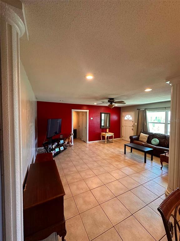 A living room features red accent walls, tile flooring, a ceiling fan, and a brown sofa — 8923 110TH LANE, SEMINOLE, FL