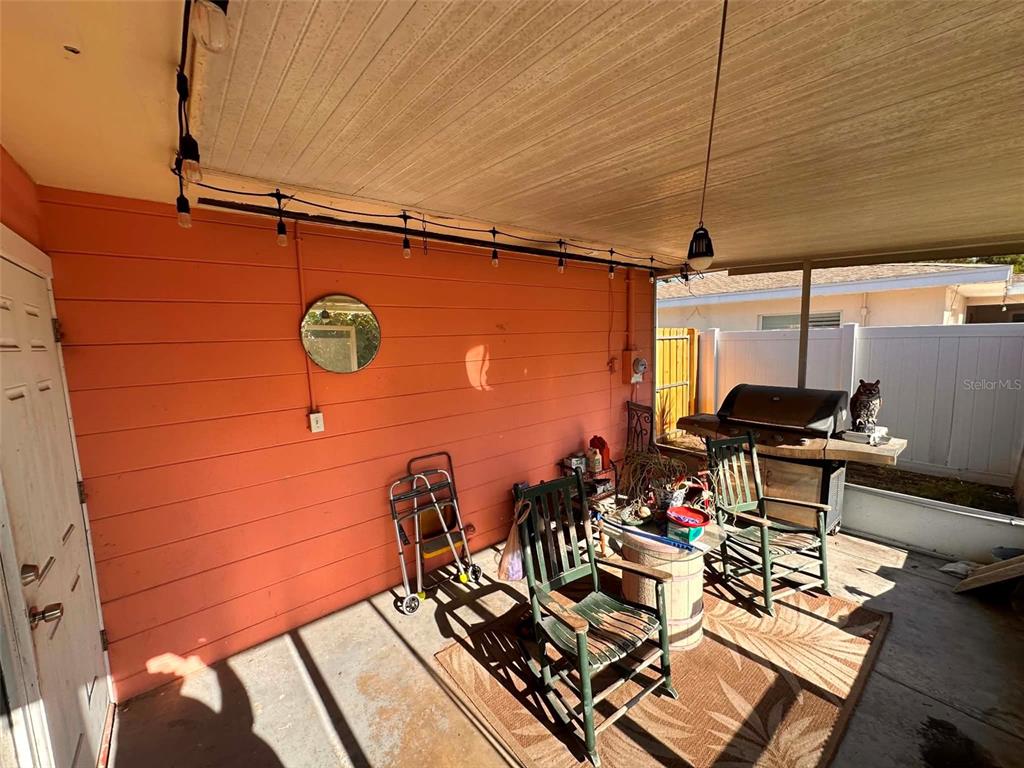 A covered outdoor patio features orange horizontal siding, string lights, and a grill area — 8923 110TH LANE, SEMINOLE, FL