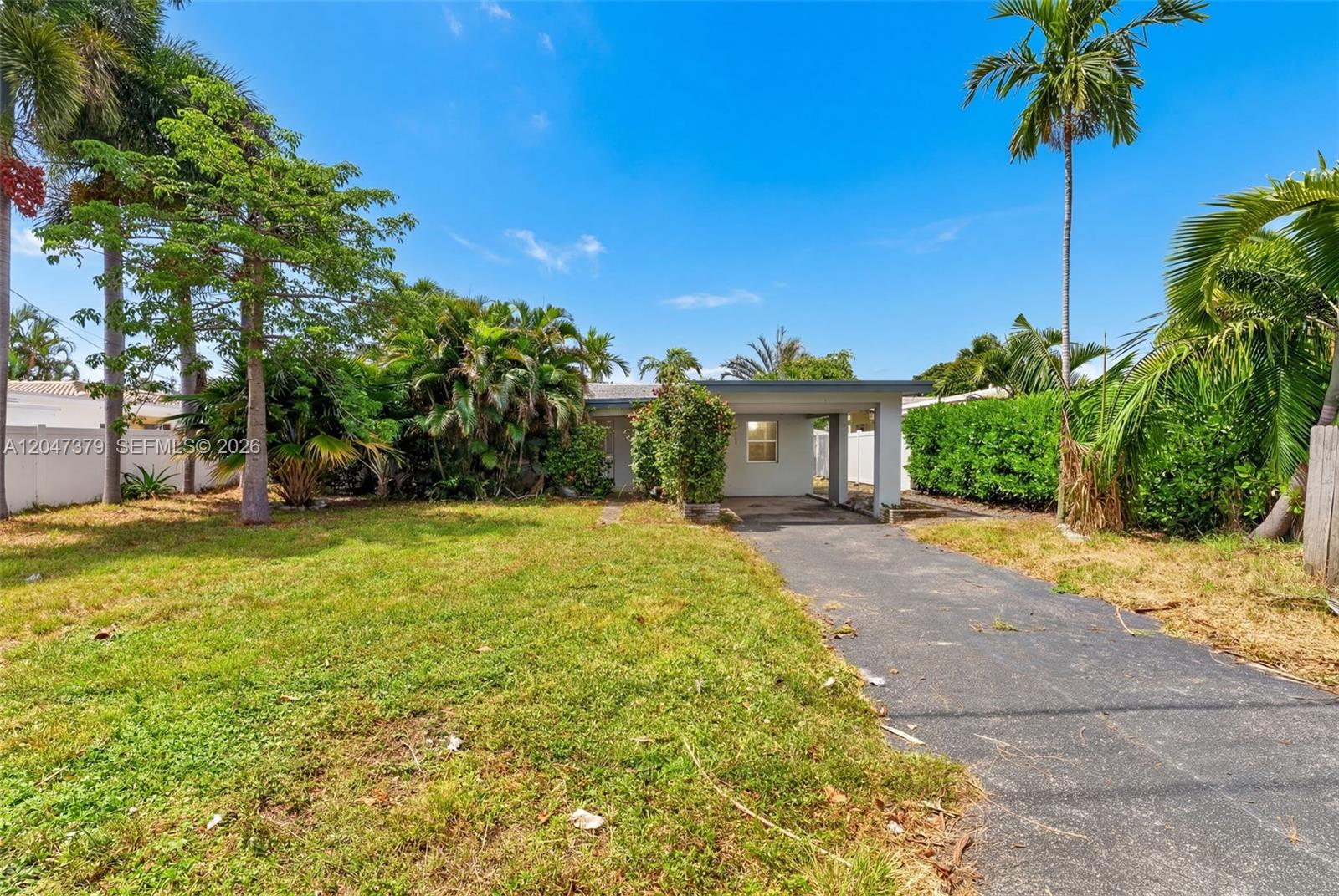 A single-story house with a carport and a front lawn surrounded by tropical trees — 2472 SE 13th Ct, Pompano Beach FL 33062, POMPANO BEACH, FL